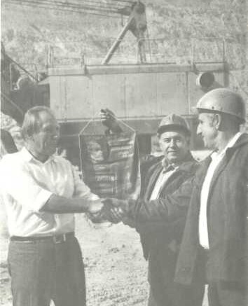 Секретарь парткома открытого рудника А. К. Петухов поздравляет победителей соревнования машинистов экскаватора кавалеров 